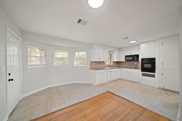 2931 Barksdale Dr, Houston, TX 77093 - kitchen with black appliances, light tile patterned flooring, tasteful backsplash, and white cabinets
