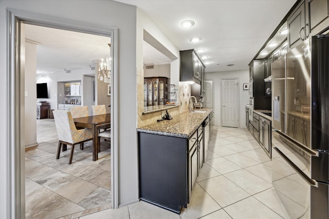 3350 Mccue Rd Unit 1504, Houston, TX 77056 - kitchen with stainless steel appliances, light stone countertops, a chandelier, and light tile patterned floors