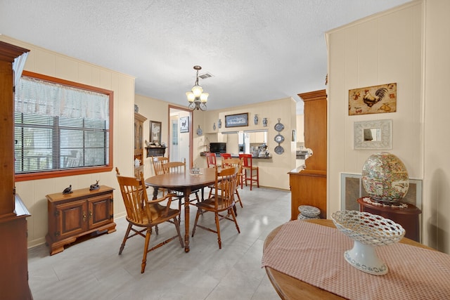 2970 Spanish Oaks Dr, Brenham, TX 77833 - dining space featuring a chandelier, a textured ceiling, and wood walls