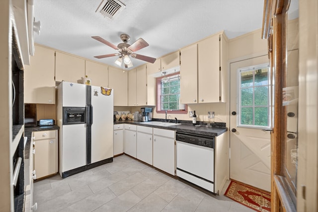 2970 Spanish Oaks Dr, Brenham, TX 77833 - kitchen with white appliances, cream cabinets, dark countertops, ceiling fan, and a textured ceiling