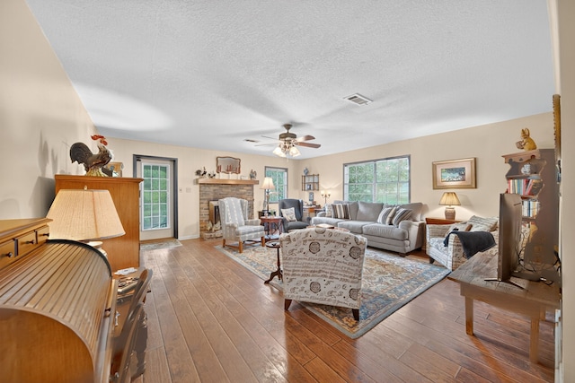 2970 Spanish Oaks Dr, Brenham, TX 77833 - living area with ceiling fan, a textured ceiling, hardwood / wood-style floors, and a stone fireplace