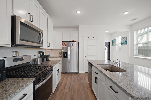 5958 First Blush Dr, Katy, TX 77493 - kitchen with appliances with stainless steel finishes, dark wood-type flooring, white cabinets, tasteful backsplash, and light stone counters