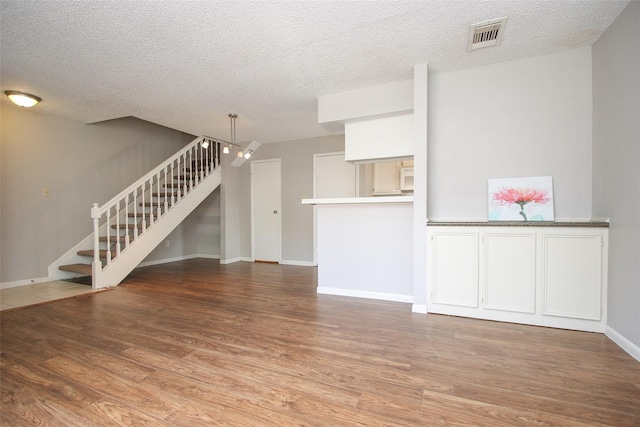 10615 Briar Forest Dr Unit 402, Houston, TX 77042 - unfurnished living room featuring wood finished floors, stairs, and a textured ceiling