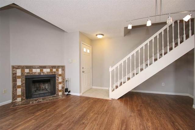 10615 Briar Forest Dr Unit 402, Houston, TX 77042 - unfurnished living room featuring stairs, a textured ceiling, wood finished floors, rail lighting, and a fireplace