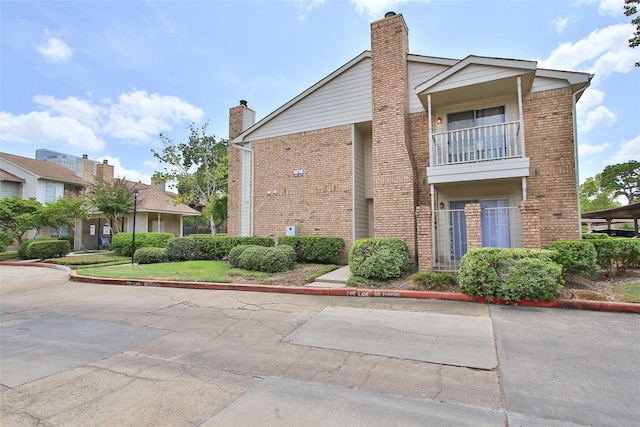10615 Briar Forest Dr Unit 402, Houston, TX 77042 - view of home's exterior featuring brick siding, a chimney, and a balcony