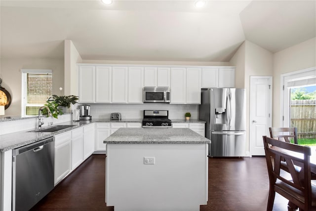 9906 Deborah Colony Ln, Humble, TX 77396 - kitchen with stainless steel appliances, lofted ceiling, decorative backsplash, white cabinets, and a center island