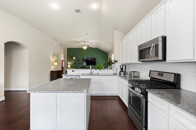 9906 Deborah Colony Ln, Humble, TX 77396 - kitchen featuring appliances with stainless steel finishes, decorative backsplash, lofted ceiling, a center island, and dark wood finished floors