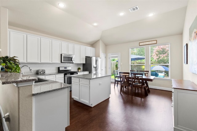 9906 Deborah Colony Ln, Humble, TX 77396 - kitchen with appliances with stainless steel finishes, tasteful backsplash, dark wood-style floors, a kitchen island, and light stone counters