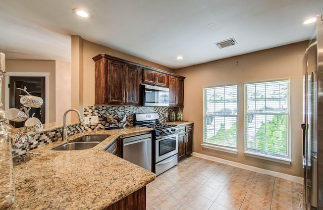 2516 Vaughn St, Houston, TX 77093 - kitchen featuring appliances with stainless steel finishes, decorative backsplash, light stone countertops, light tile patterned flooring, and recessed lighting