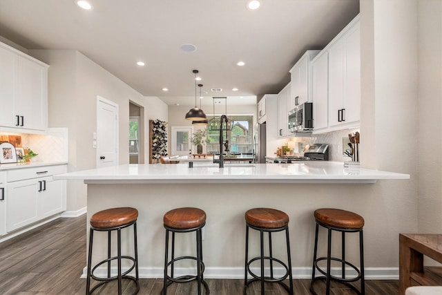 7906 Pershing Ave, Magnolia, TX 77354 - kitchen featuring stainless steel appliances, a breakfast bar, tasteful backsplash, white cabinets, and recessed lighting