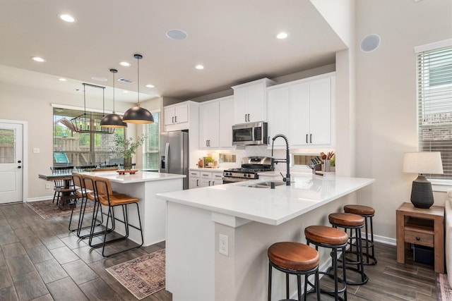 7906 Pershing Ave, Magnolia, TX 77354 - kitchen featuring appliances with stainless steel finishes, a kitchen bar, dark wood finished floors, a kitchen island, and tasteful backsplash
