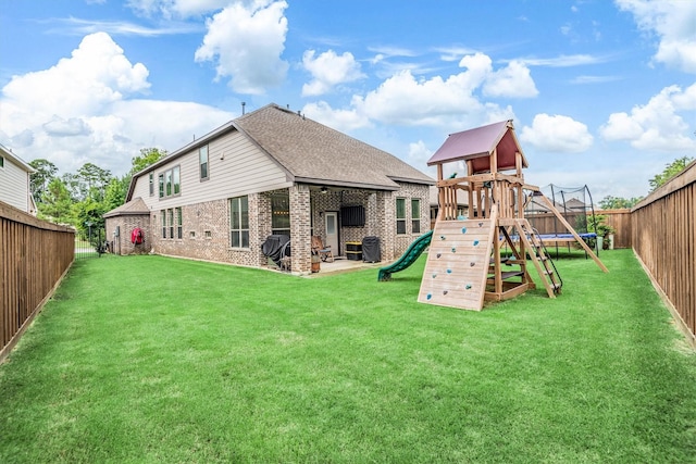 7906 Pershing Ave, Magnolia, TX 77354 - rear view of house with a playground, a trampoline, a fenced backyard, and brick siding