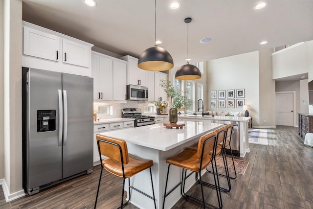 7906 Pershing Ave, Magnolia, TX 77354 - kitchen with stainless steel appliances, dark wood finished floors, a peninsula, a kitchen island, and light countertops