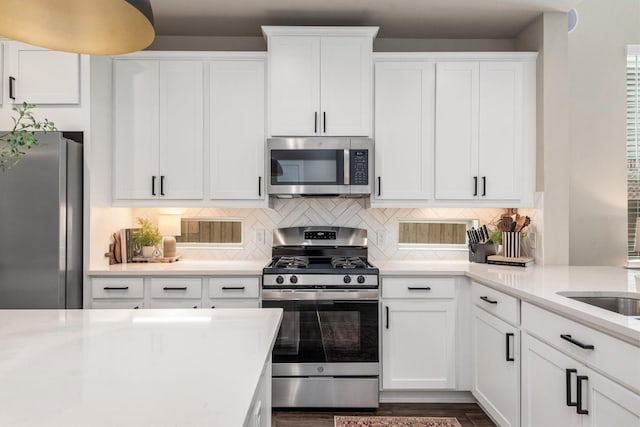7906 Pershing Ave, Magnolia, TX 77354 - kitchen with appliances with stainless steel finishes, light countertops, white cabinetry, and tasteful backsplash