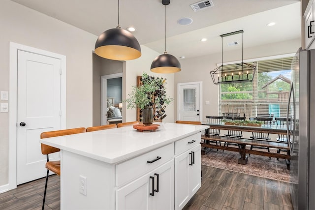 7906 Pershing Ave, Magnolia, TX 77354 - kitchen with freestanding refrigerator, a kitchen breakfast bar, dark wood-style flooring, white cabinets, and a kitchen island