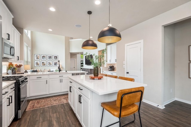 7906 Pershing Ave, Magnolia, TX 77354 - kitchen featuring gas stove, stainless steel microwave, dark wood finished floors, light countertops, and white cabinets