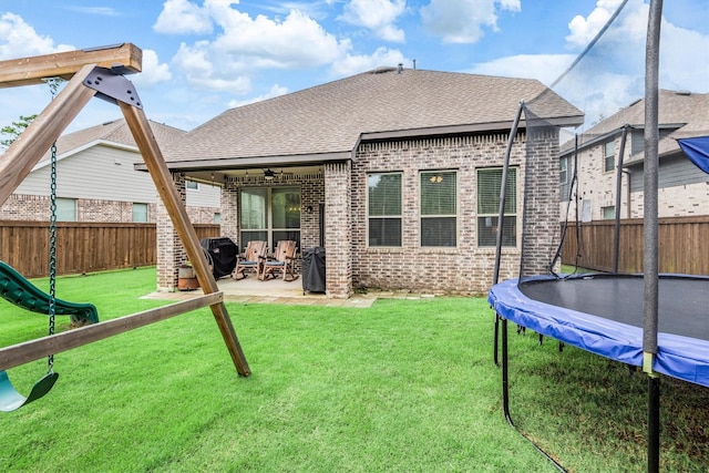 7906 Pershing Ave, Magnolia, TX 77354 - rear view of house with a trampoline, brick siding, a fenced backyard, a ceiling fan, and a patio area