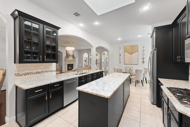 6 Inland Prairie Dr, Tomball, TX 77375 - kitchen with arched walkways, appliances with stainless steel finishes, dark cabinets, a center island, and tasteful backsplash