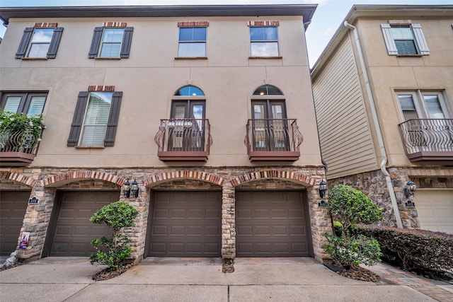 542 Bomar St, Houston, TX 77006 - view of front of house featuring a balcony, an attached garage, driveway, stucco siding, and stone siding