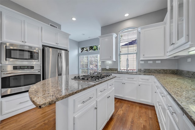 542 Bomar St, Houston, TX 77006 - kitchen featuring stainless steel appliances, white cabinetry, light wood finished floors, recessed lighting, and light stone counters