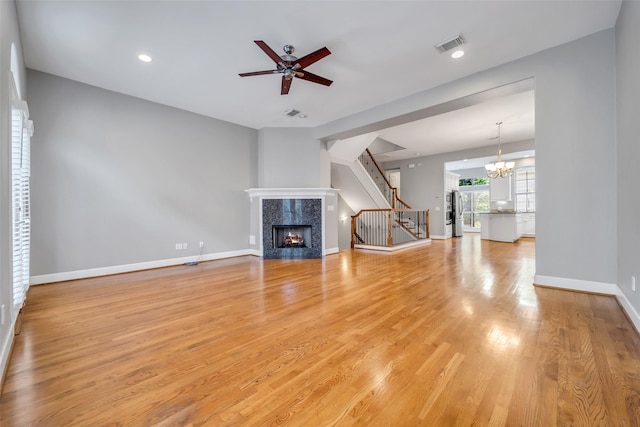 542 Bomar St, Houston, TX 77006 - unfurnished living room with stairway, a fireplace, light wood-style floors, a ceiling fan, and a chandelier