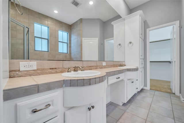 542 Bomar St, Houston, TX 77006 - bathroom featuring double vanity, a tile shower, tile patterned flooring, a spacious closet, and decorative backsplash