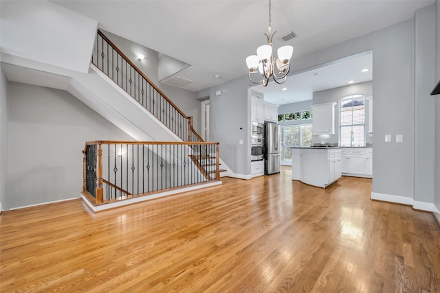 542 Bomar St, Houston, TX 77006 - unfurnished living room with light wood-style flooring, a chandelier, and stairs