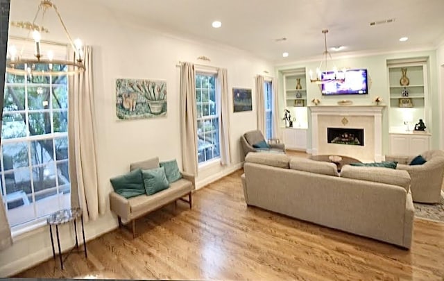 2006 Buffalo Ter, Houston, TX 77019 - living room featuring wood finished floors, a chandelier, built in shelves, a fireplace, and ornamental molding