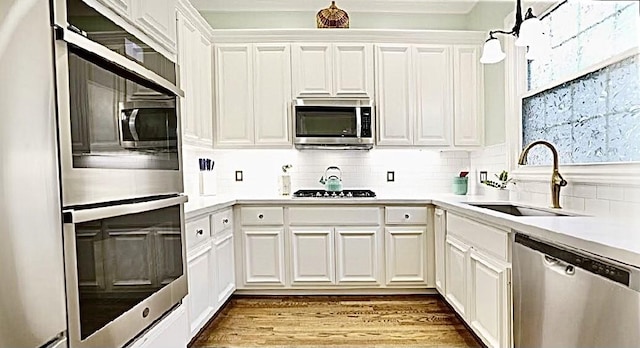 2006 Buffalo Ter, Houston, TX 77019 - kitchen with appliances with stainless steel finishes, tasteful backsplash, white cabinetry, light countertops, and wood finished floors