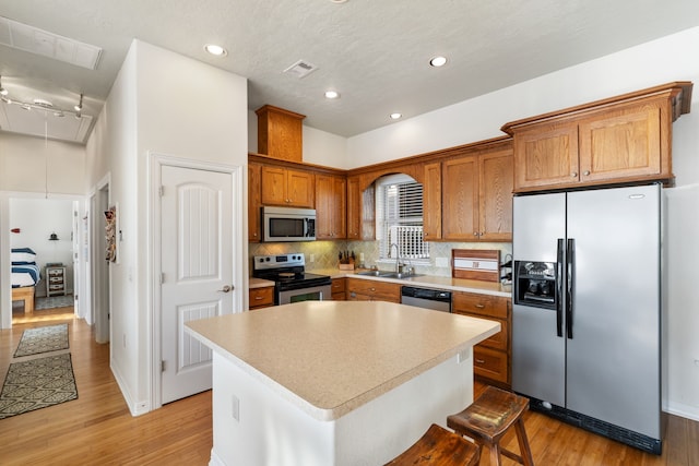 129 Lakeshore Dr, Onalaska, TX 77360 - kitchen with stainless steel appliances, a center island, light wood-style flooring, brown cabinetry, and backsplash