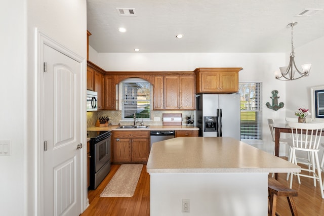 129 Lakeshore Dr, Onalaska, TX 77360 - kitchen with stainless steel appliances, light wood finished floors, a kitchen island, tasteful backsplash, and light countertops