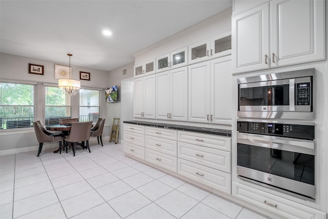 9706 Broadley Dr, Sugar Land, TX 77498 - kitchen with stainless steel appliances, a chandelier, light tile patterned floors, white cabinets, and glass insert cabinets