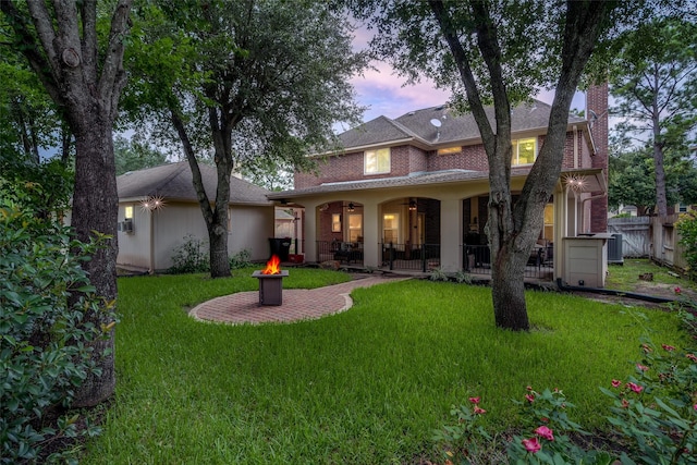 9706 Broadley Dr, Sugar Land, TX 77498 - back of property at dusk with a fire pit, a patio, a chimney, and brick siding