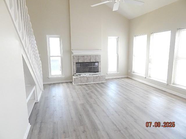 21315 Gulf Dr, Galveston, TX 77554 - unfurnished living room with ceiling fan, high vaulted ceiling, a fireplace, plenty of natural light, and wood finished floors