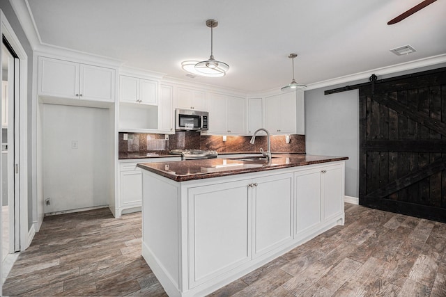 3014 Bayou Dr, La Porte, TX 77571 - kitchen with stainless steel microwave, ceiling fan, tasteful backsplash, stove, and white cabinetry