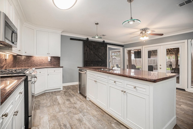 3014 Bayou Dr, La Porte, TX 77571 - kitchen with appliances with stainless steel finishes, a ceiling fan, backsplash, white cabinets, and a barn door