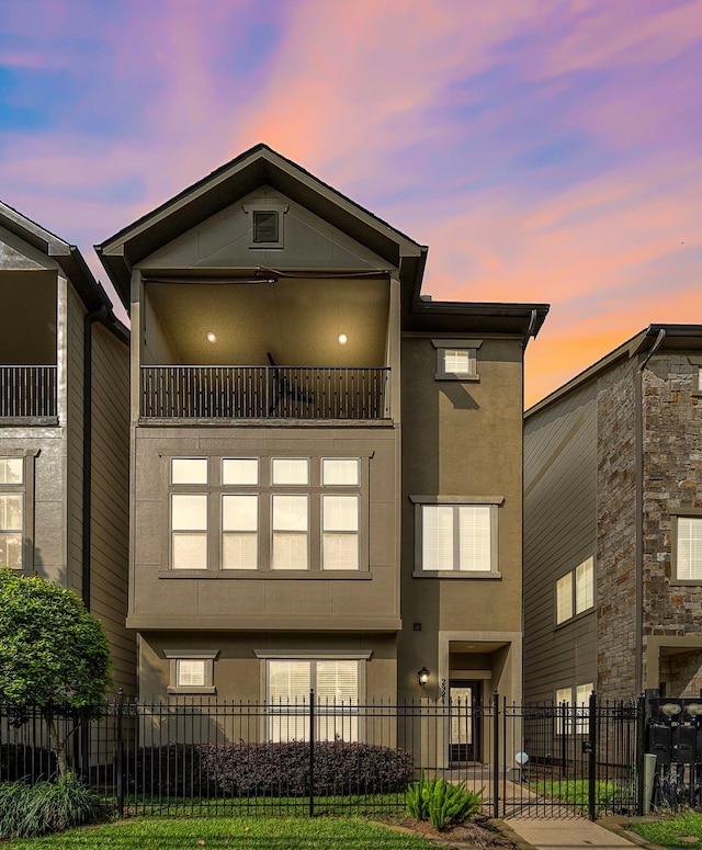 2924 Leeland St, Houston, TX 77003 - back of property at dusk featuring stucco siding, a balcony, and a fenced front yard