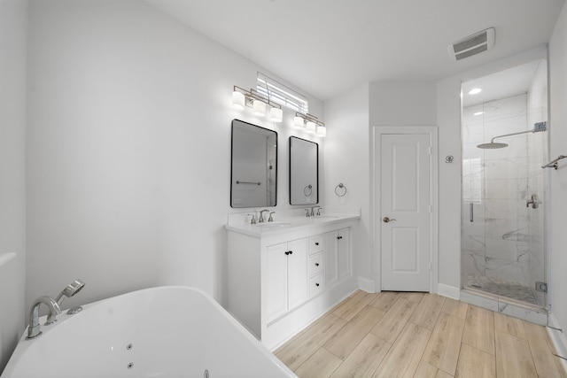 2924 Leeland St, Houston, TX 77003 - full bath with a tub with jets, a shower stall, double vanity, wood finished floors, and recessed lighting
