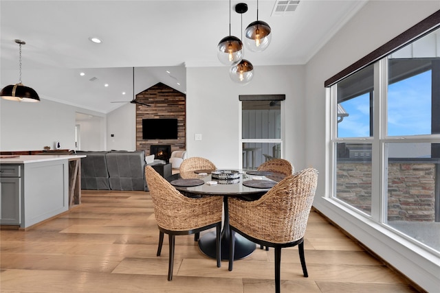 110 Penguin Pt, Point Blank, TX 77364 - dining area with light wood-style flooring, lofted ceiling, a large fireplace, ornamental molding, and recessed lighting