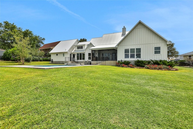 110 Penguin Pt, Point Blank, TX 77364 - view of front facade featuring board and batten siding, a chimney, a sunroom, a front yard, and an outdoor pool