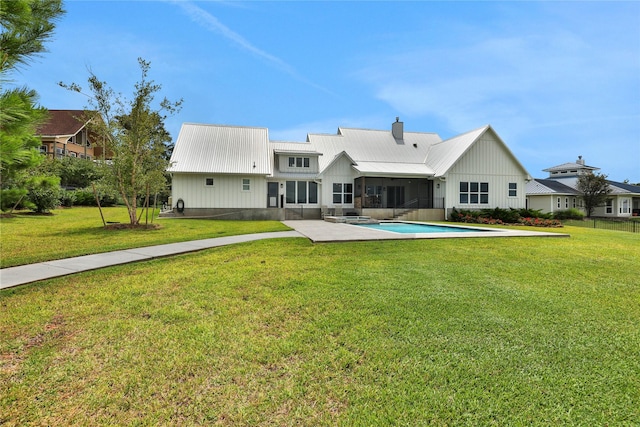 110 Penguin Pt, Point Blank, TX 77364 - back of house featuring a sunroom, a metal roof, a lawn, board and batten siding, and a chimney