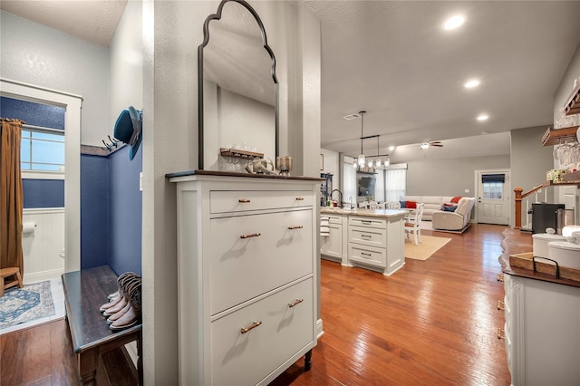 10252 Sunset Ln, Conroe, TX 77385 - kitchen with white cabinets, light wood-style floors, open floor plan, a ceiling fan, and decorative light fixtures