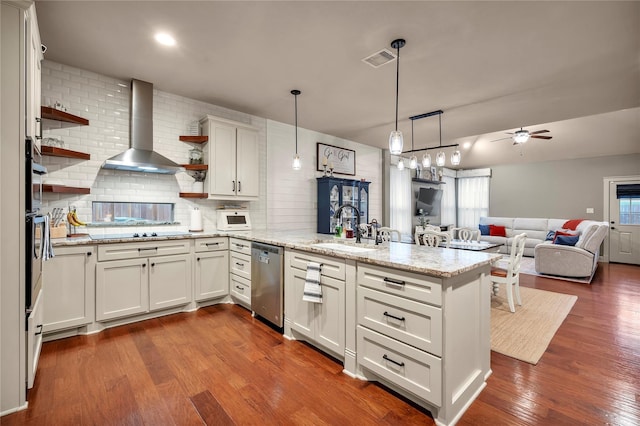 10252 Sunset Ln, Conroe, TX 77385 - kitchen with wall chimney range hood, a peninsula, open shelves, appliances with stainless steel finishes, and dark wood finished floors