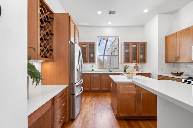 2310 Arabelle St, Houston, TX 77007 - kitchen with stainless steel refrigerator with ice dispenser, decorative backsplash, light countertops, wood finished floors, and brown cabinets