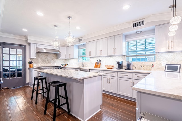 3217 Parkwood Dr, Houston, TX 77021 - kitchen with light stone counters, dark wood-style flooring, crown molding, a kitchen bar, and a center island
