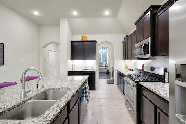 22223 Ebbets Field Dr, Spring, TX 77389 - kitchen with stainless steel appliances, arched walkways, light stone counters, and recessed lighting