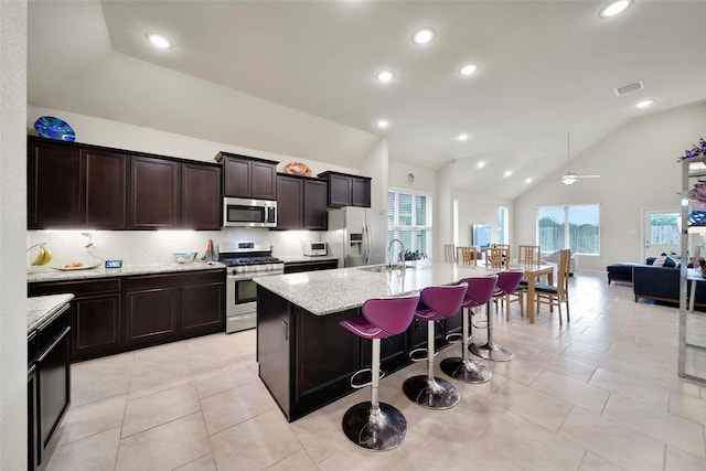 22223 Ebbets Field Dr, Spring, TX 77389 - kitchen with stainless steel appliances, a kitchen island with sink, plenty of natural light, ceiling fan, and high vaulted ceiling