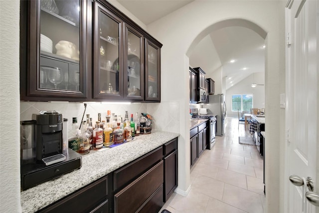22223 Ebbets Field Dr, Spring, TX 77389 - bar featuring arched walkways, stainless steel appliances, backsplash, vaulted ceiling, and light tile patterned floors