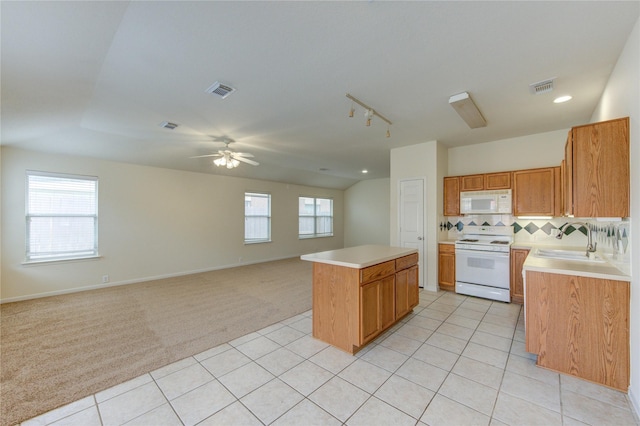 20218 Cypresswood Gln, Spring, TX 77373 - kitchen featuring white appliances, a center island, light countertops, light carpet, and rail lighting