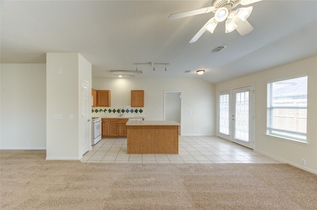20218 Cypresswood Gln, Spring, TX 77373 - kitchen featuring white gas range oven, a center island, light tile patterned floors, and light colored carpet